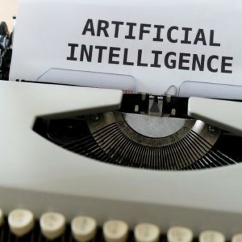Eine altmodische Schreibmaschine, die den Schriftzug "Artificial Intelligence" tippt.